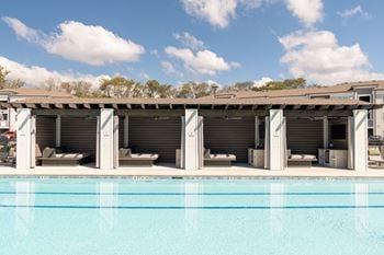 Sundeck with lounge chairs, tables with chairs, and four cabanas