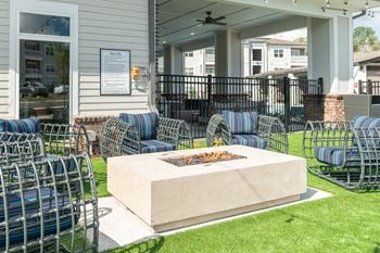 Outdoor beer garden styled with decorative lighting, private seating, fire pit, corn hole, and covered grilling stations