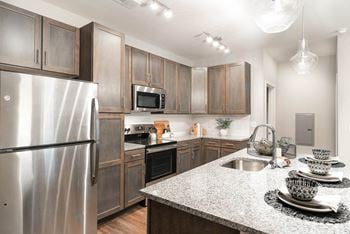 Stainless steel kitchen appliances including top freezer with ice maker, electric radiant smooth cooktop range, dishwasher with advanced dry cycle, microwave, and disposal.