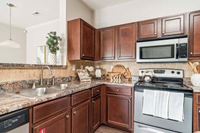Lenoir City apartment for rent - A kitchen with brown cabinets and a black dishwasher.