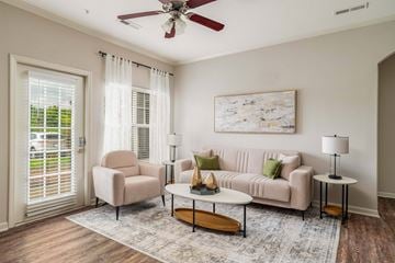 Lenoir City apartment for rent - A living room with a beige couch, a chair, a coffee table, and a painting on the wall.