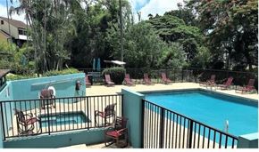 Aiea apartment for rent - A pool with a hot tub and chairs on a balcony.