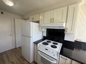 Honolulu condo for rent - A kitchen with a white fridge, stove and oven.