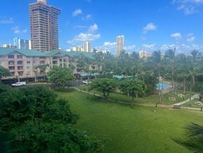 Honolulu condo for rent - a large grassy area with trees and buildings in the background
