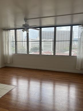 Honolulu apartment for rent - A room with a ceiling fan and a window overlooking a cityscape.