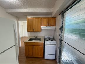 Honolulu apartment for rent - A kitchen with wooden cabinets and white appliances.
