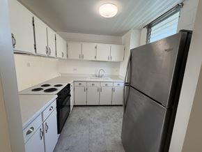 Honolulu condo for rent - A kitchen with white cabinets and a black refrigerator.