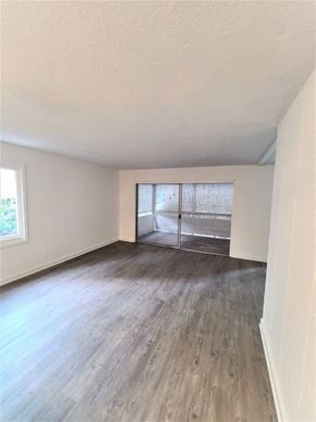 Honolulu condo for rent - A room with wooden flooring and a sliding glass door.