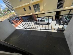 Honolulu apartment for rent - A balcony with a black railing and a white car parked on the street.