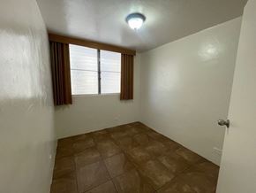 Honolulu apartment for rent - A room with brown tiles and a window with brown curtains.