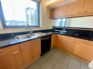 Honolulu condo for rent - A kitchen with wooden cabinets and black countertops.