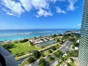 Honolulu condo for rent - A view from a high-rise building overlooking a coastal cityscape with a clear blue sky.
