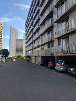 Honolulu apartment for rent - a parking lot in front of a tall building