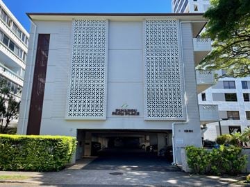 Honolulu condo for rent - A white building with a large window and a garage door.