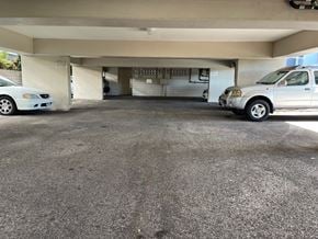 Honolulu condo for rent - A car is parked in a garage with a white car to its left.