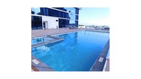 Honolulu condo for rent - a large swimming pool next to a tall building