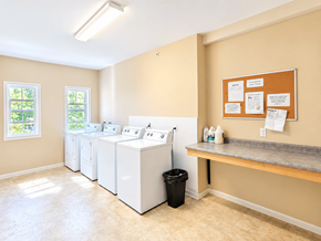 South Burlington apartment for rent - A laundry room with a washer and dryer, a trash can, and a bulletin board.
