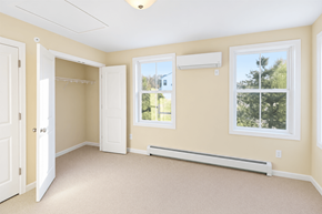 South Burlington apartment for rent - A room with a carpeted floor, a window with a view of trees, and a white door.