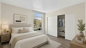 Seattle apartment for rent - A bedroom with a large bed, a nightstand, a window with a view, a wardrobe, and a plant.