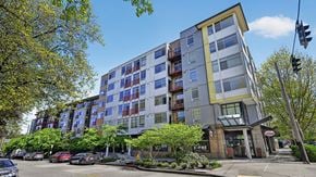 Seattle apartment for rent - A modern multi-story apartment building with a parking lot in front.