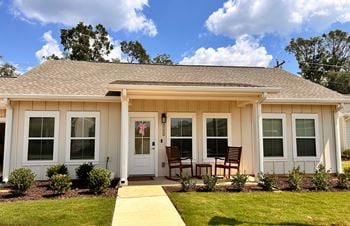 A small white house with a brown roof and a white door
