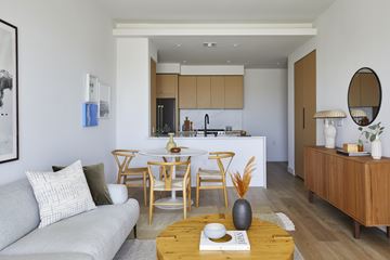 Los Angeles apartment for rent - A modern living room with a grey couch, wooden chairs, and a coffee table with a book and vase on it.