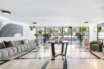 Los Angeles apartment for rent - A modern living room with a long sofa, a coffee table, and a large abstract painting on the wall.