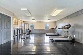 Wichita apartment for rent - a gym with treadmills and weights in a large room with a door
