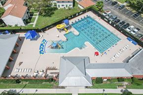 Naples apartment for rent - An aerial view of a swimming pool surrounded by a parking lot and buildings.