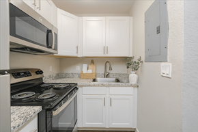 Naples apartment for rent - A kitchen with white cabinets and a black stove top oven.