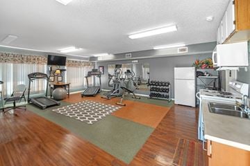 Nixa apartment for rent - A spacious room with a variety of exercise equipment and a kitchen area.