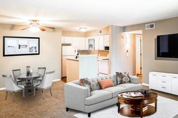 Shawnee Mission apartment for rent - A living room with a grey couch, a coffee table, and a dining table with chairs.