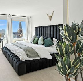 Tulsa apartment for rent - A bedroom with a large bed and a view of a city skyline.