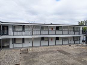 Lakewood apartment for rent - A building with a grey facade and a tree in front.