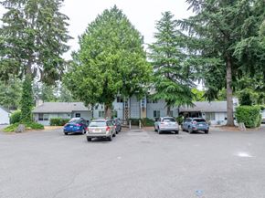 Lakewood apartment for rent - A parking lot with cars and trees in the background.