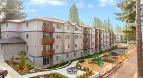 Seattle apartment for rent - A modern apartment complex with a playground and trees.