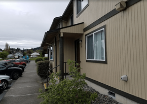 Anacortes apartment for rent - a building with a sidewalk and cars parked in front of it