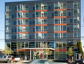 Seattle apartment for rent - A modern building with a glass facade and a red awning at the entrance.