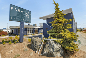 Anacortes apartment for rent - a pine tree in front of a building with a sign that