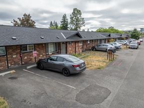 Lakewood apartment for rent - A grey car is parked in a parking lot in front of a brick building.