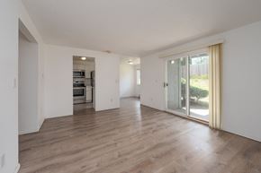 Tacoma apartment for rent - A spacious room with wooden flooring and a sliding glass door leading to a garden.