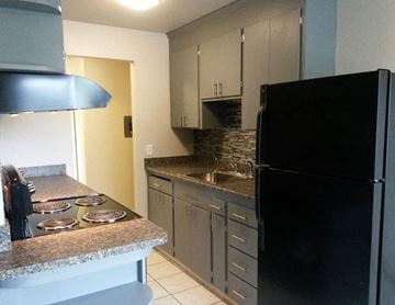 Seattle apartment for rent - A black refrigerator sits in a kitchen with a granite countertop and stove.
