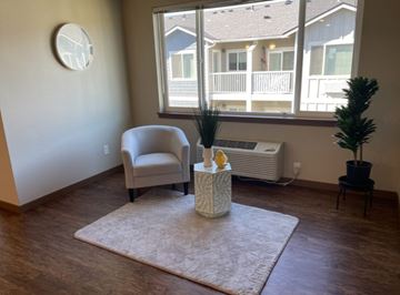 Wenatchee apartment for rent - A living room with a chair, a table with a vase, and a window.