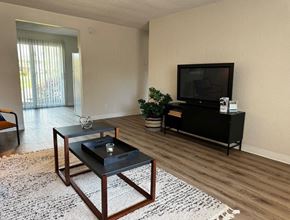 Springfield apartment for rent - A black coffee table with a candle on it sits in the middle of a room with a flat screen TV mounted on the wall.