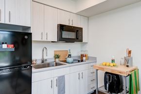 Seattle apartment for rent - a kitchen with white cabinets and a sink and a microwave