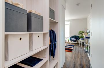 Seattle apartment for rent - a walk in closet with white cabinets and shelves and a living room with a table