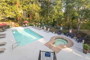 Lake Oswego apartment for rent - A pool with a hot tub and chairs in a wooded area.