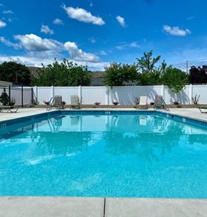 Wenatchee apartment for rent - A swimming pool surrounded by a white fence and trees.