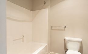 Lynnwood apartment for rent - A white toilet sits next to a white bathtub in a small bathroom.