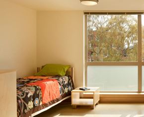 Seattle apartment for rent - A bedroom with a bed, nightstand, and window overlooking a tree-filled area.